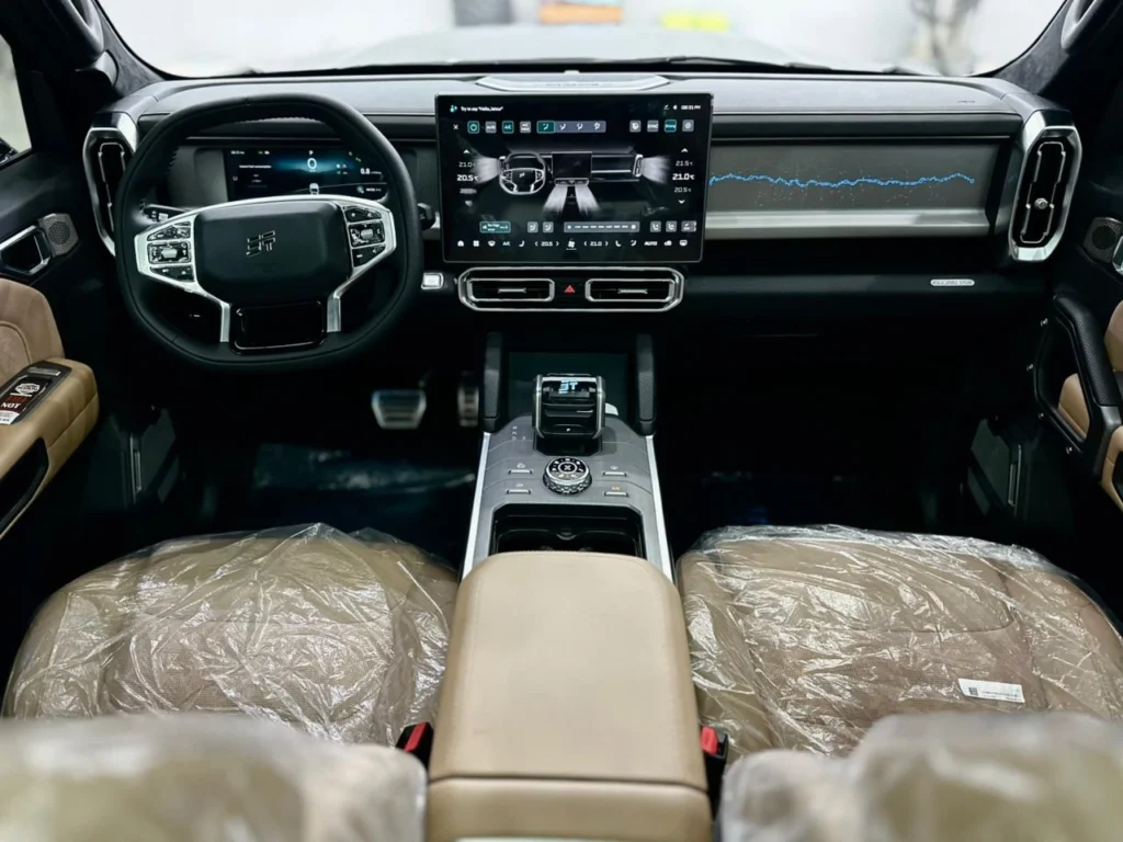 Full dashboard of the Jetour T2 2025 seen from the rear seats, with beige upholstery either side